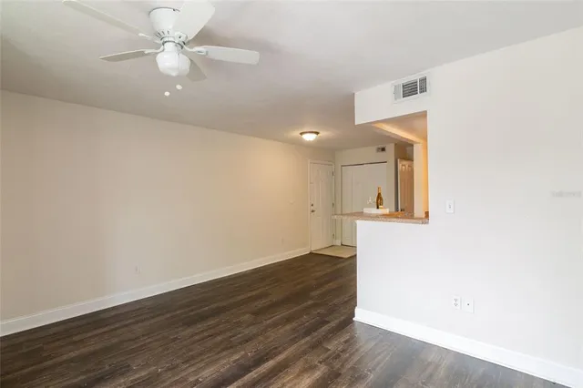 an empty room with wooden floor and fan