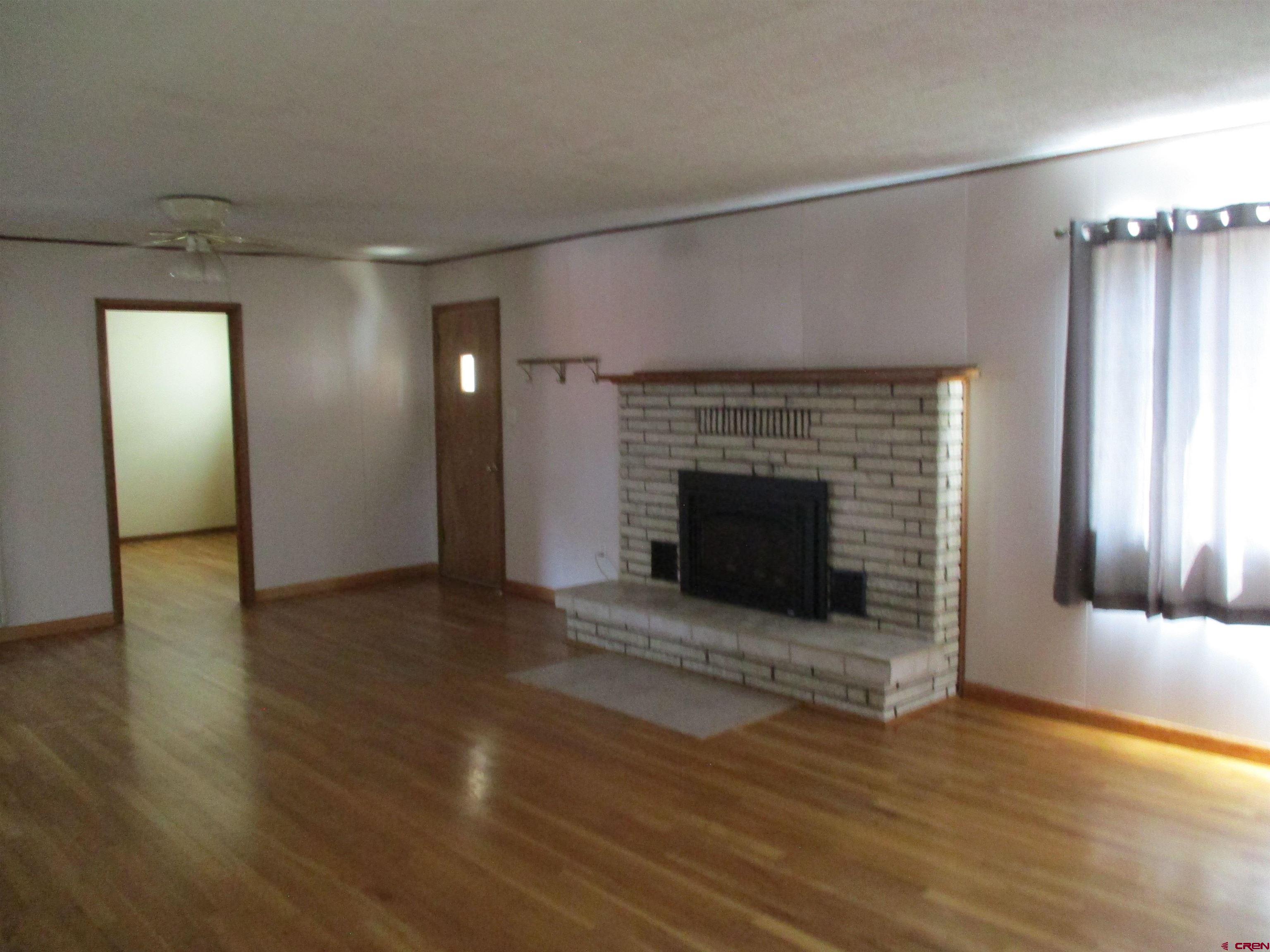 1102 Bluff Street Delta, CO 81416 - Photo 8 of 14 an empty room with wooden floor fireplace and windows