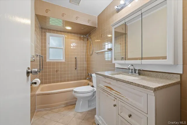 a bathroom with a granite countertop sink toilet mirror and bathtub