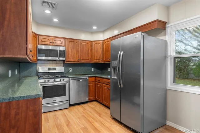 a kitchen with stainless steel appliances granite countertop a refrigerator a sink and a stove