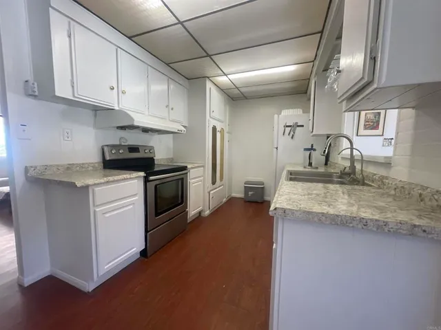 a kitchen with granite countertop a sink stainless steel appliances and white cabinets