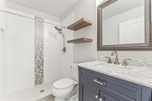 a bathroom with a granite countertop sink toilet and shower