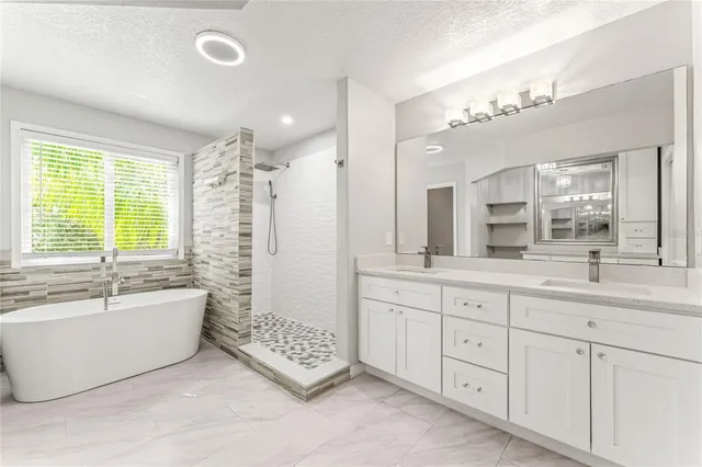 a spacious bathroom with double vanity a window a bathtub and a double vanity sink
