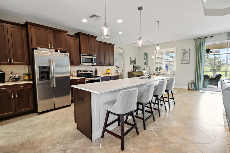 570 Gossamer Wing Way Sebastian, FL 32958 - Photo 15 of 36 a kitchen with stainless steel appliances kitchen island granite countertop a dining table chairs refrigerator and microwave
