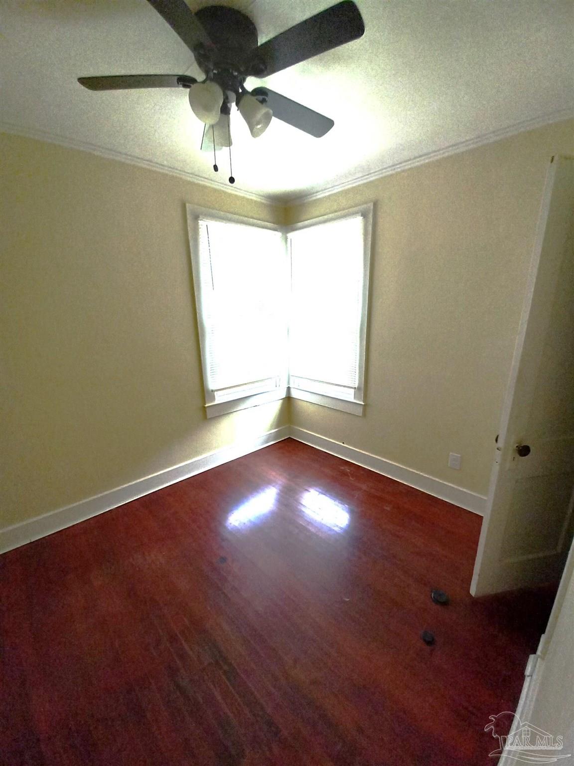 1120 South Old Corry Field Road Pensacola, FL 32507 - Photo 8 of 10 an empty room with wooden floor and windows