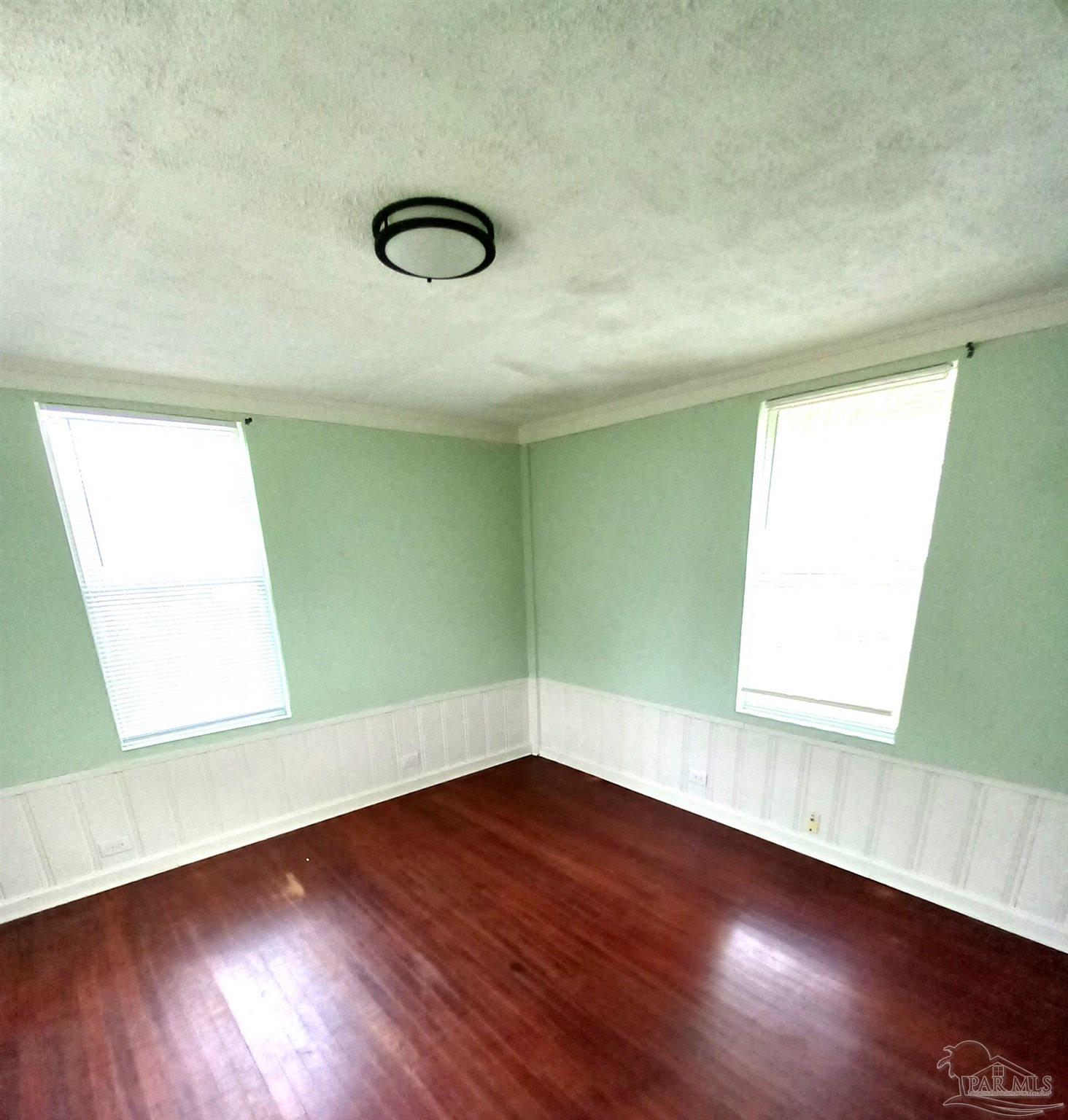 1120 South Old Corry Field Road Pensacola, FL 32507 - Photo 9 of 10 an empty room with wooden floor and windows