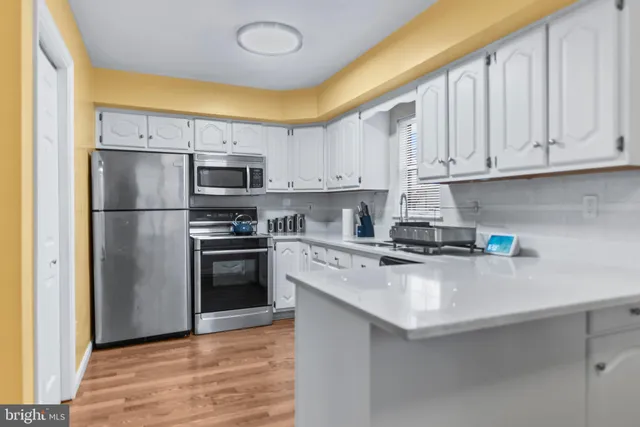 a kitchen with stainless steel appliances granite countertop a refrigerator sink and white cabinets
