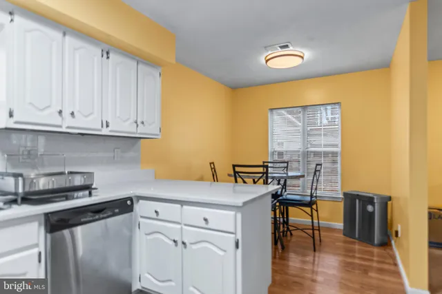 a kitchen with stainless steel appliances white cabinets and wooden floor