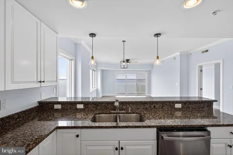 a kitchen with granite countertop a sink and white cabinets