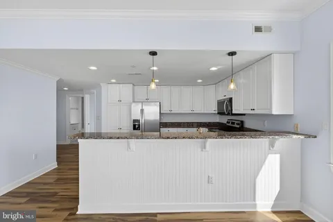 a large white kitchen with kitchen island a sink a stove and a refrigerator