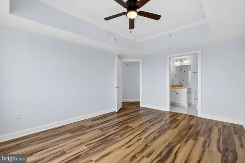 a view of a hallway with wooden floor and a bathroom
