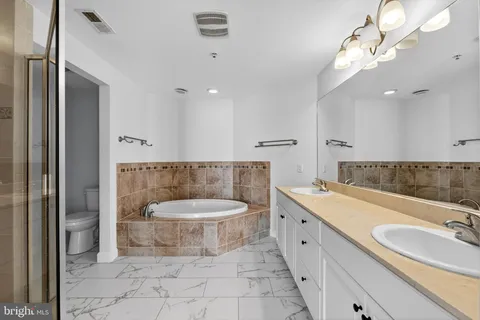 a spacious bathroom with a tub sink and mirror