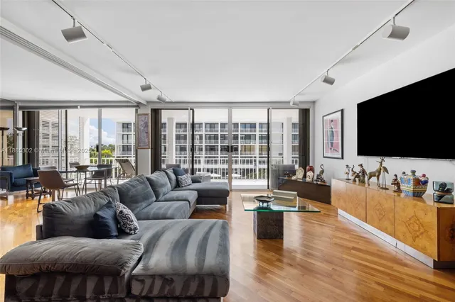 a living room with furniture floor to ceiling window hardwood floor and a flat screen tv