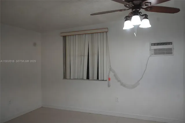 an empty room with a ceiling fan and window
