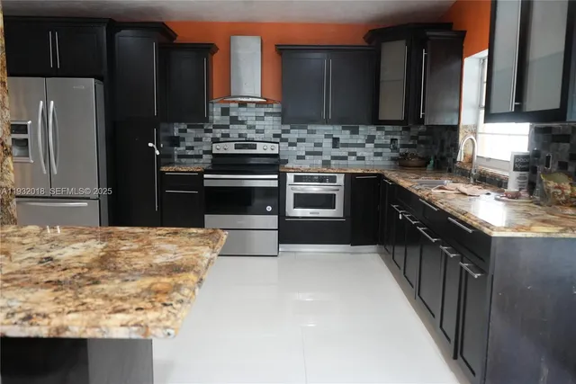 a kitchen with stainless steel appliances kitchen island granite countertop a sink stove and refrigerator