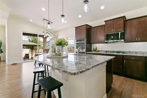 a kitchen with stainless steel appliances granite countertop a kitchen island a stove and a sink