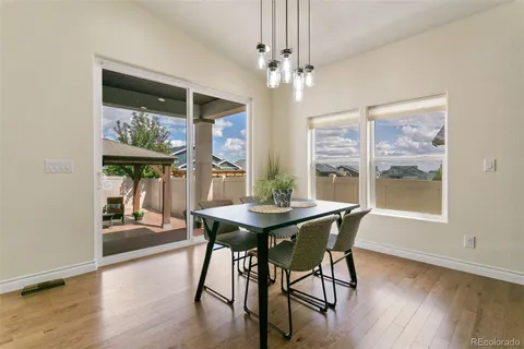a dining room with wooden floor a chandelier a wooden table and chairs