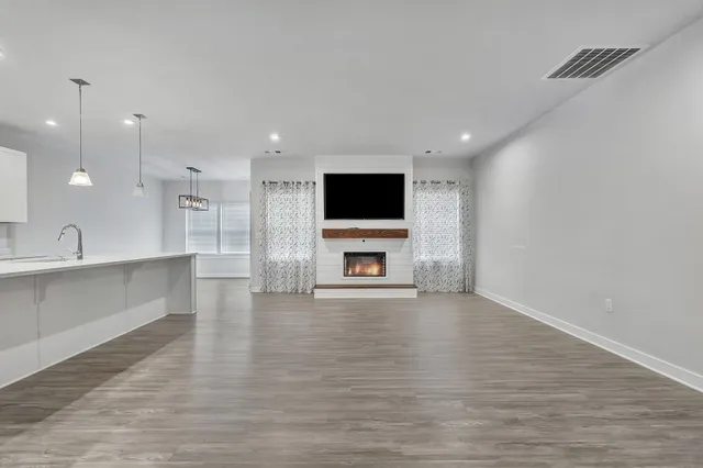 a large kitchen with stainless steel appliances kitchen island granite countertop a stove a refrigerator and a fireplace with wooden floor