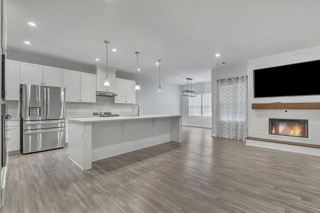 a large white kitchen with wooden floors stainless steel appliances and cabinets