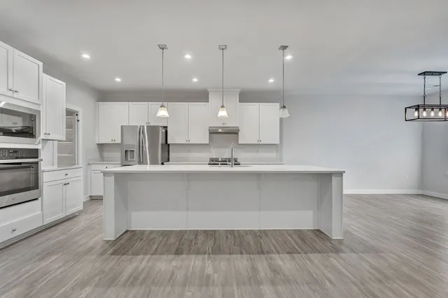 a large white kitchen with lots of counter space wooden floor and appliances