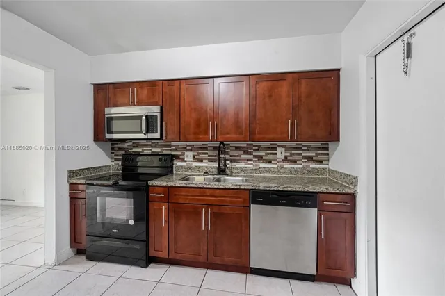 a kitchen with stainless steel appliances granite countertop a stove a sink and a microwave
