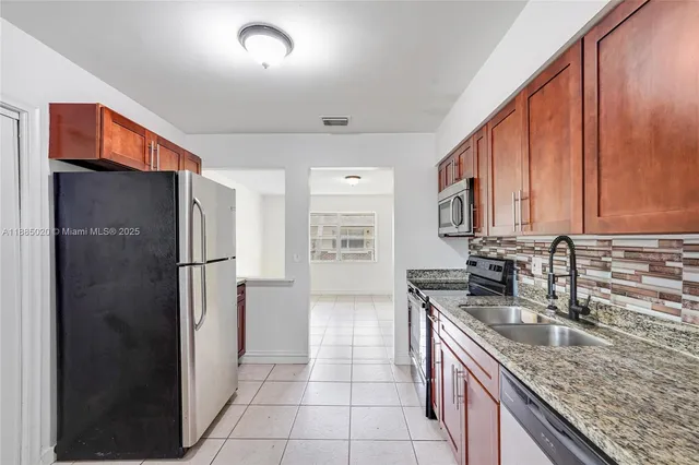 a kitchen with stainless steel appliances granite countertop a refrigerator and a sink