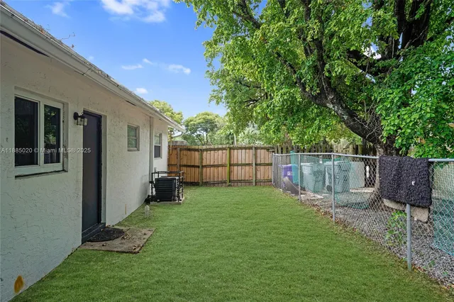 a view of a backyard with wooden fence and a bench