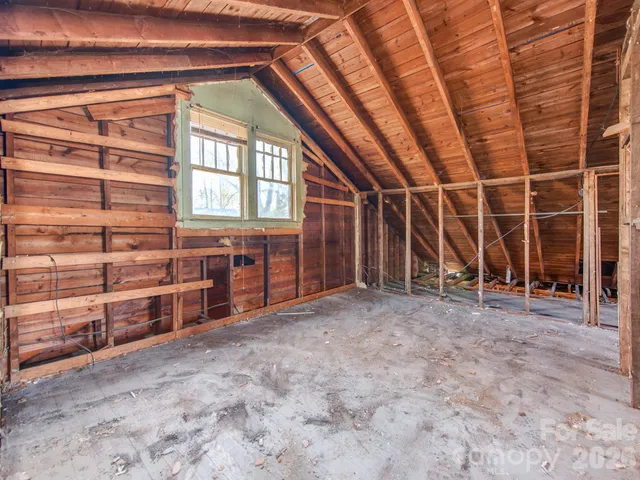 a view of an empty room with wooden roof and windows