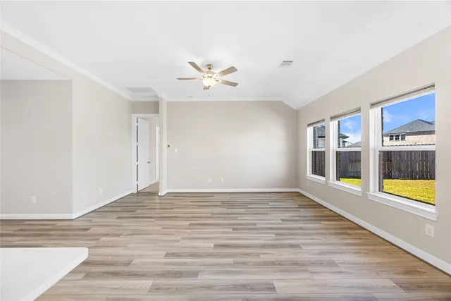 a view of an empty room with a window and wooden floor