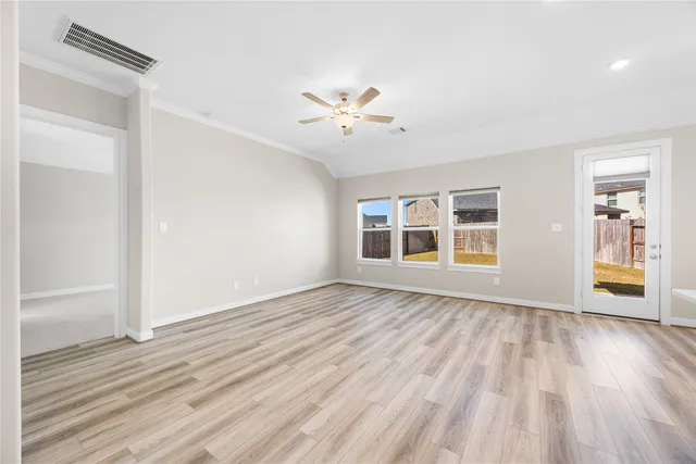 an empty room with wooden floor chandelier fan and windows