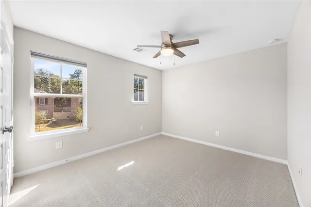 an empty room with a window and ceiling fan