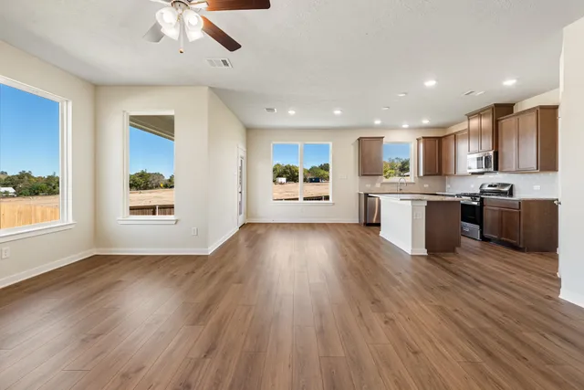 a large kitchen with stainless steel appliances kitchen island a large counter space and wooden floors