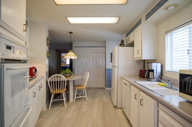 a kitchen with stainless steel appliances granite countertop a dining table chairs a refrigerator and a chandelier