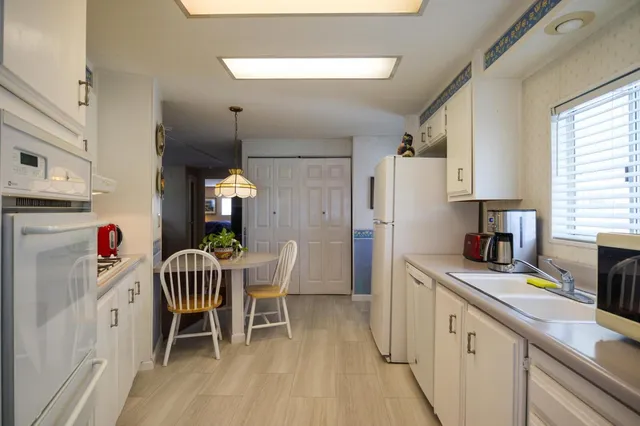 a kitchen with stainless steel appliances granite countertop a dining table chairs a refrigerator and a chandelier