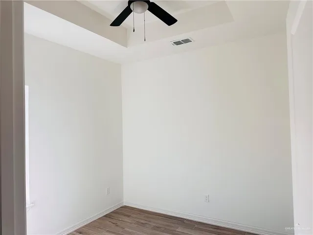 an empty room with a ceiling fan and wooden floor
