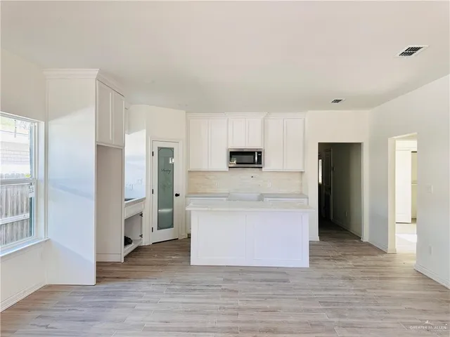a view of kitchen with stainless steel appliances wooden floor and window