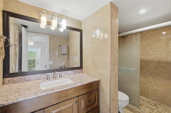 a bathroom with a granite countertop sink toilet and shower