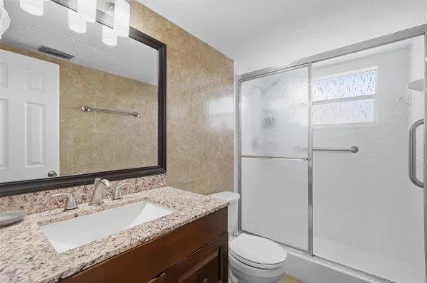 a bathroom with a granite countertop sink toilet and shower
