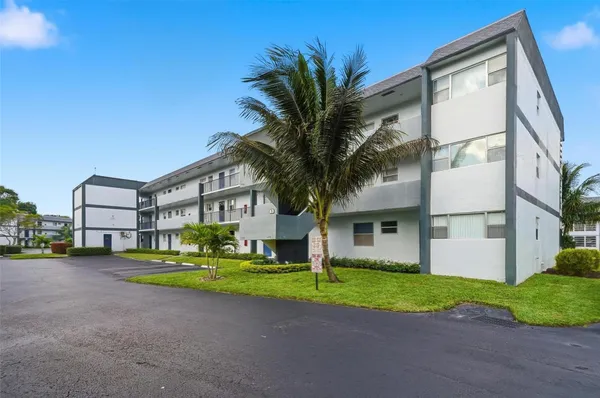 a front view of a house with garden and trees