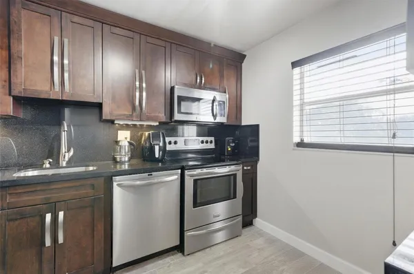 a kitchen with stainless steel appliances granite countertop a stove a sink and a microwave