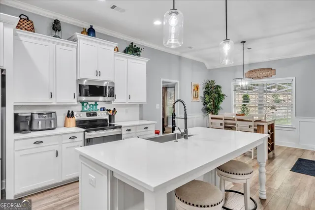 a kitchen with kitchen island a white cabinets and appliances