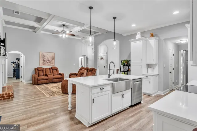 a large white kitchen with a stove a sink a refrigerator and chandelier