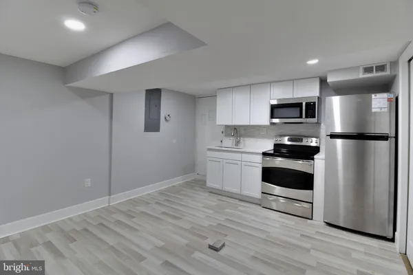a kitchen with a refrigerator stove and wooden floor