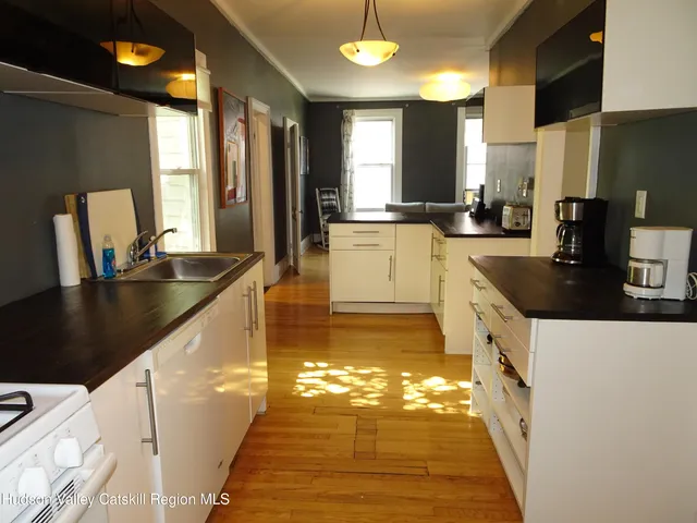 a kitchen with granite countertop a sink a stove top oven a counter space and cabinets