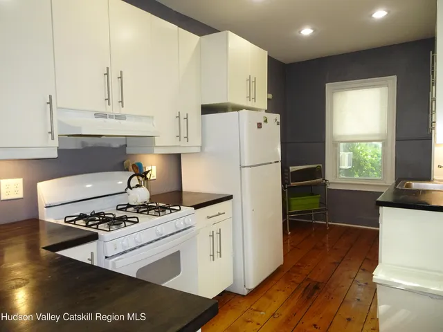 a kitchen with a refrigerator a stove cabinets and wooden floor