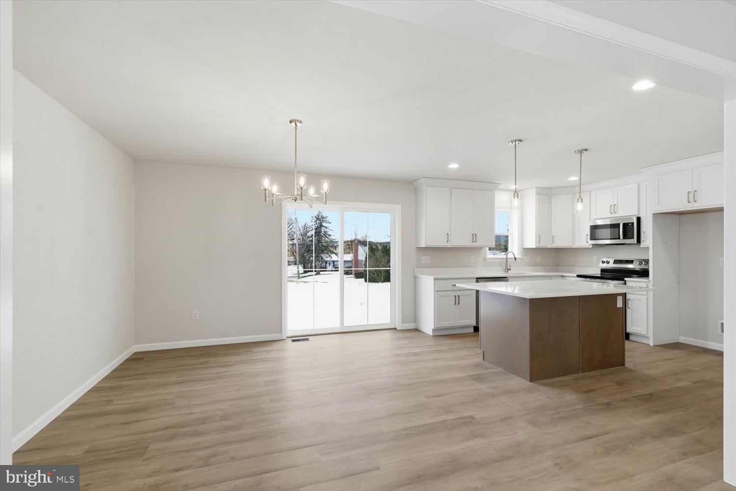 228 Hockersville Road Hershey, PA 17033 - Photo 5 of 36 a large white kitchen with kitchen island a sink dishwasher a refrigerator and white cabinets with wooden floor