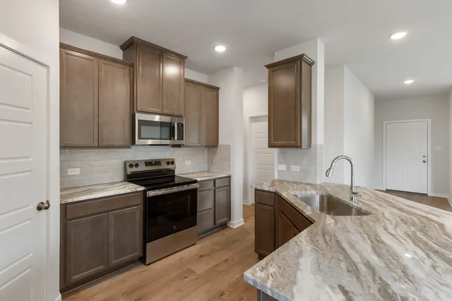 a kitchen with stainless steel appliances granite countertop a sink stove and microwave
