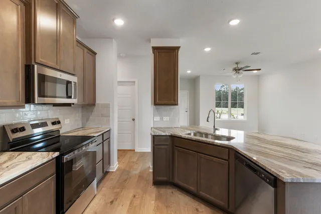 a kitchen with stainless steel appliances granite countertop a sink stove and cabinets