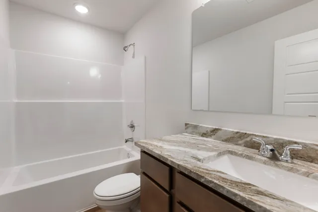 a bathroom with a granite countertop sink a toilet and bathtub