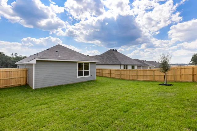 a view of a yard with wooden fence and a large tree